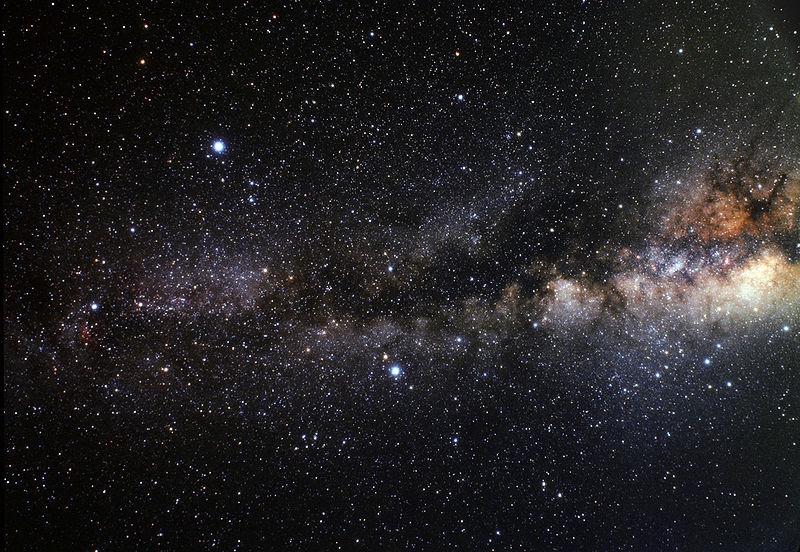 Dense star field with cloudy Milky Way running horizontally across it, and three bright stars.