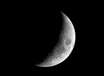Crescent moon with many mountains, seas, and craters visible.