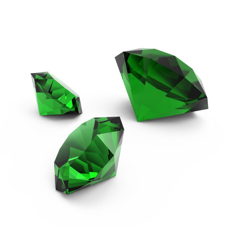 Enlarged view of three brilliant green faceted gemstones.