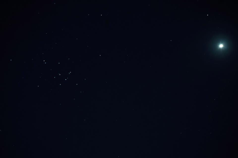 Cluster of stars on black background with fuzzy white dot near them.
