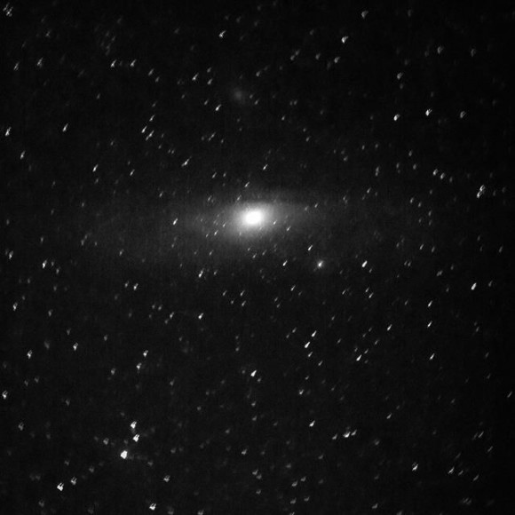 Fuzzy oval patch of light, thicker in the middle, in a field of stars.