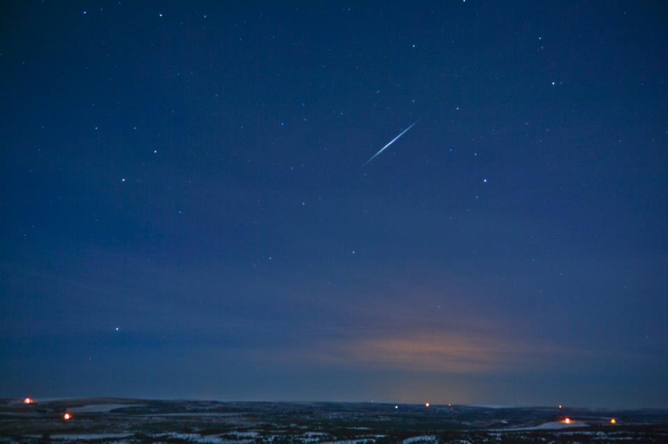 Small flash of light in a dark blue sky with stars.