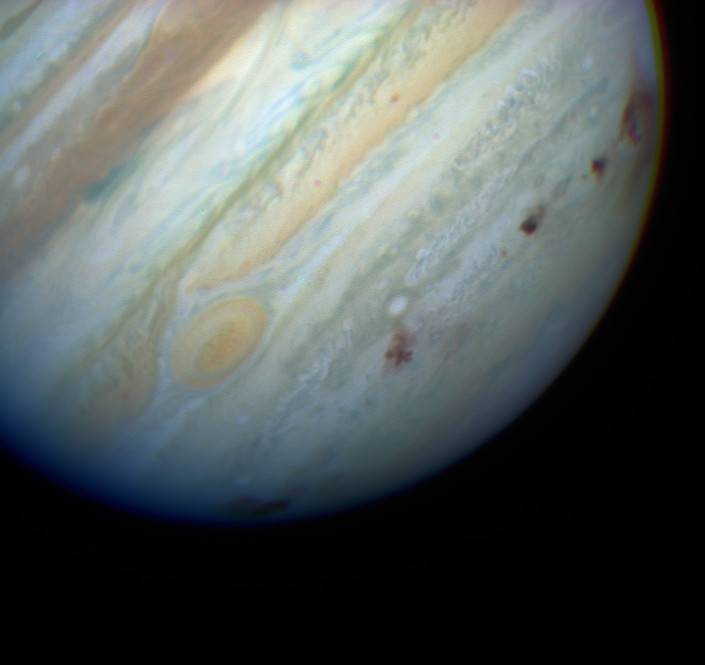 Closeup of Jupiter in color with dark spots below Great Red Spot.