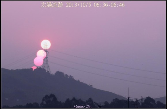 Pink sky with three images of the sun in a line behind a power line pylon.