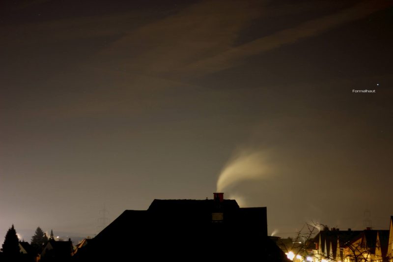 A darkened skyline, with smoke from a chimney blowing sideways and a single star above.