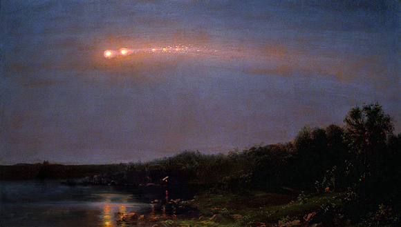 Orange streak with multiple large yellow dots along it in dark blue sky over wooded landscape.
