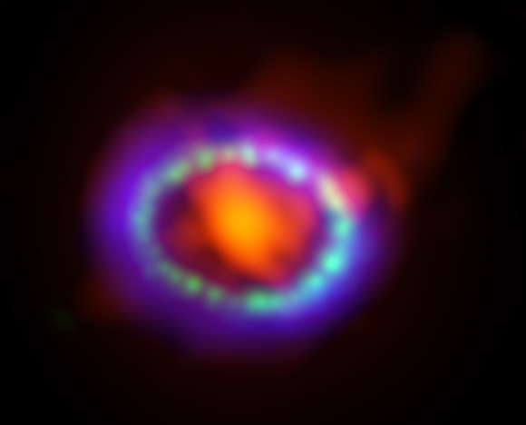 Composite image of supernova 1987A. ALMA data (in red) shows newly formed dust in the center of the remnant. HST (in green) and Chandra (in blue) show the expanding shockwave. Image credit: Alexandra Angelich (NRAO/AUI/NSF); NASA Hubble; NASA Chandra 