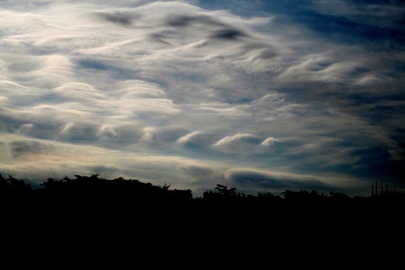 Two rows of wave clouds one above the other in cloudy sky.