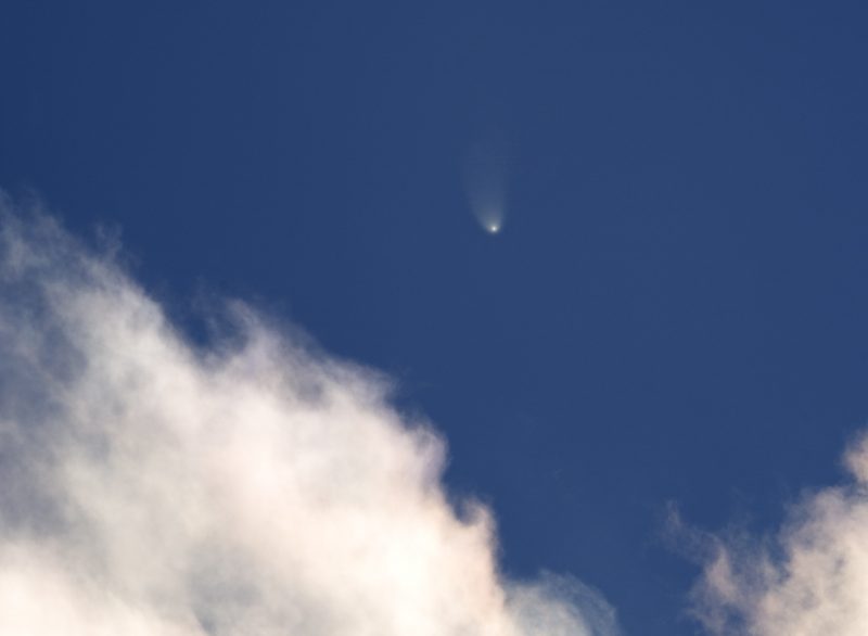 Comet in blue sky with clouds.