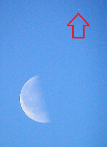 Moon with small white dot above it with arrow.