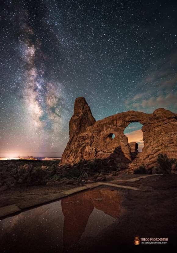 Rocky spires with Milky Way in the background. There is water in the foreground, where the rocks and the stars are reflected.