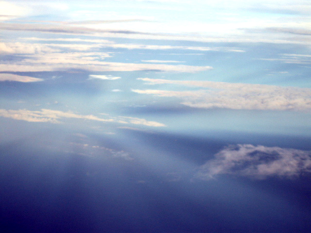 Rays converging from above and below point of view in cloudy sky.
