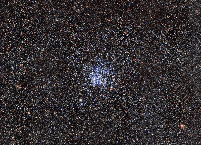 Wild Duck Cluster: A dense star field with many bright blue stars at the center and scattered red, yellow and blue stars.