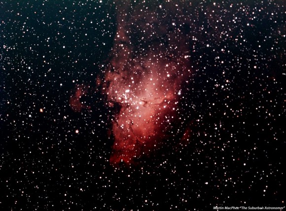 Irregular red cloud of gas in a dense star field.