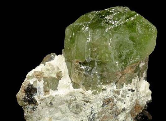 Lump of translucent green rock attached to brownish gray rock.