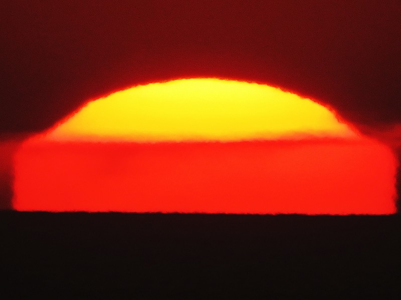 Flattened and semicircle of sun bright yellow on top similar to a sunny-side-up egg.