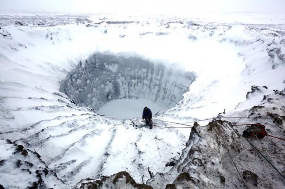 A Russian scientist prepares to descend into a mystery crater in Siberia in November. More holes have since been found.  PHOTOGRAPH BY VLADIMIR PUSHKAREV, THE SIBERIAN TIMES