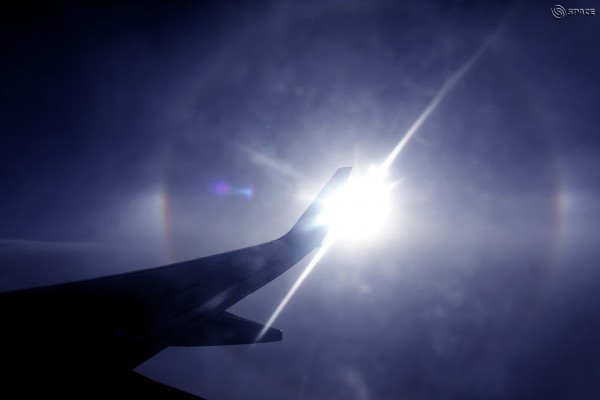 Airplane tail blocking brilliant sun with halo with 2 bright spots at either side.