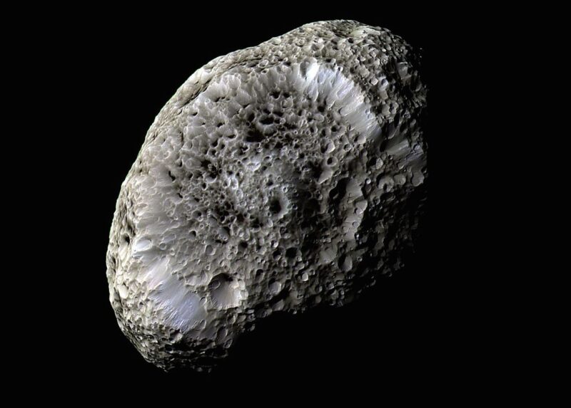 Irregular small grayish moon with craters and a sponge-like appearance.