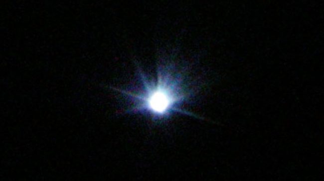 Large bright white dot with bluish rays coming out.