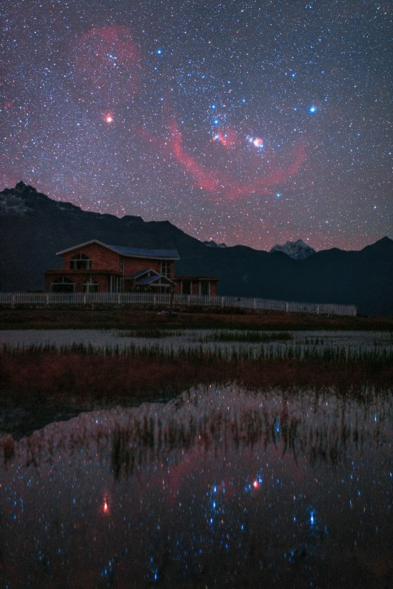 Orion rising over Tibet. Gyirong Valley, Tibet, China. As you know Orion always comes up sideways, But this single deep exposure brings out many sky wonders normally beyond human perception. The red circle across all constellation Orion is Barnard's Loop. The Horsehead nebula is also visible near the famous belt stars, and to the right is the great Orion nebula. 