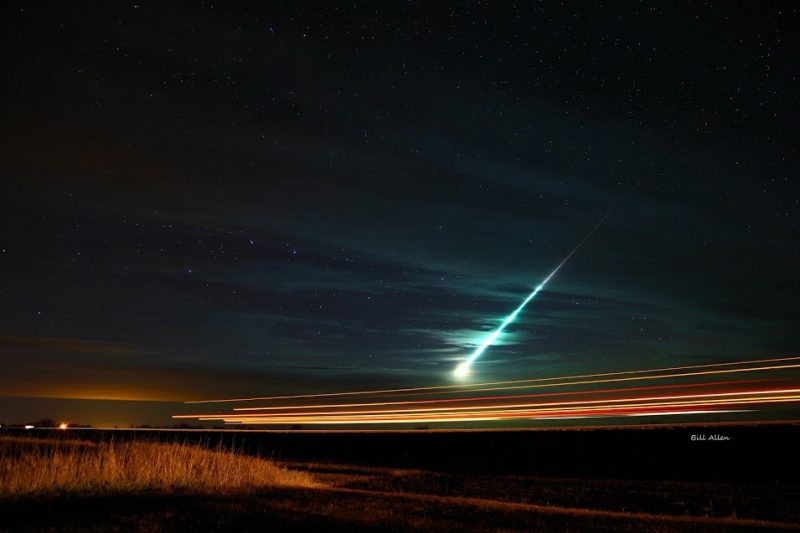 Brilliant green streak seen through thin clouds with white explosion at lower end.