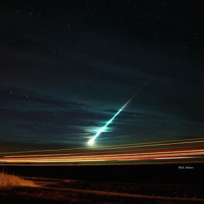 Brilliant green streak seen through thin clouds with white explosion at lower end.