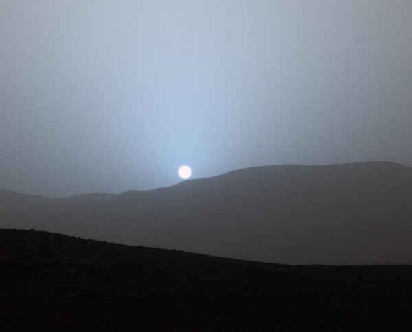 Sunset in Mars' Gale Crater. NASA's Curiosity Mars rover captured the sun setting on April 15, 2015 from the rover's location in Gale Crater. The color has been calibrated and white-balanced to remove camera artifacts. Mastcam sees color very similarly to what human eyes see, although it is actually a little less sensitive to blue than people are. Dust in the Martian atmosphere has fine particles that permit blue light to penetrate the atmosphere more efficiently than longer-wavelength colors. That causes the blue colors in the mixed light coming from the sun to stay closer to sun's part of the sky, compared to the wider scattering of yellow and red colors. Image via NASA/JPL-Caltech/MSSS
