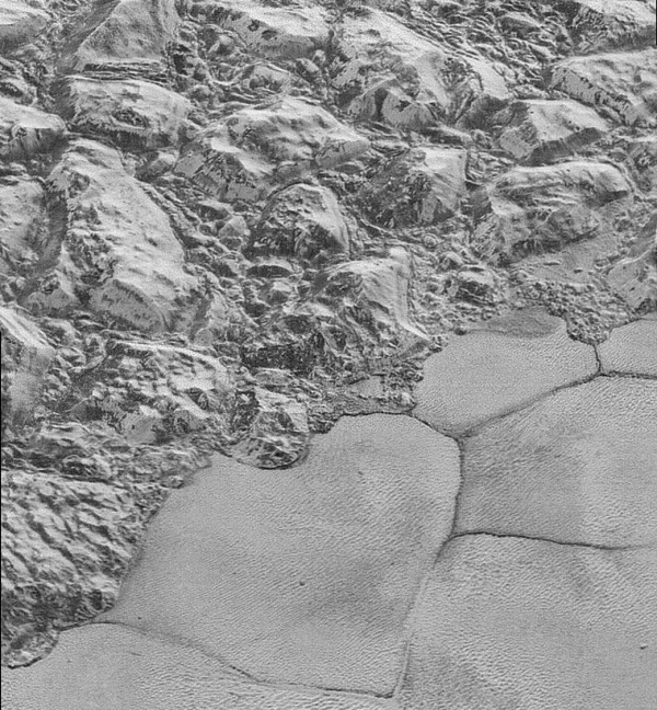 View larger. | NASA calls this image 'the mountainous shoreline of Sputnik Planum.' It's not a shoreline as on Earth, of course; it's a place where two kinds of ice meet. The mountainous region - informally named al-Idrisi mountains - is made of great blocks of Pluto’s water-ice crust. Some stand as much as 1.5 miles high. The mountains end abruptly at the shoreline of the informally named Sputnik Planum, where the soft, nitrogen-rich ices of the plain form a nearly level surface. 