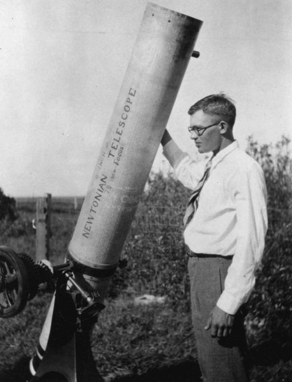 Young man standing next to a long cylinder pointed upward.