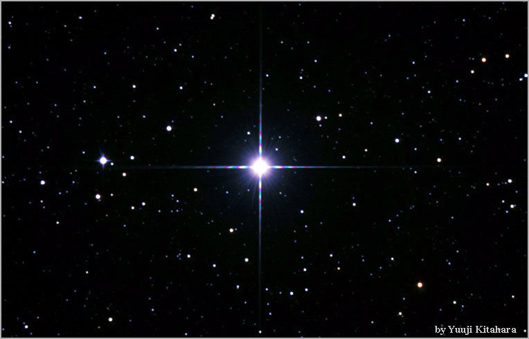 Very bright star with spikes in the middle of a black field of stars.