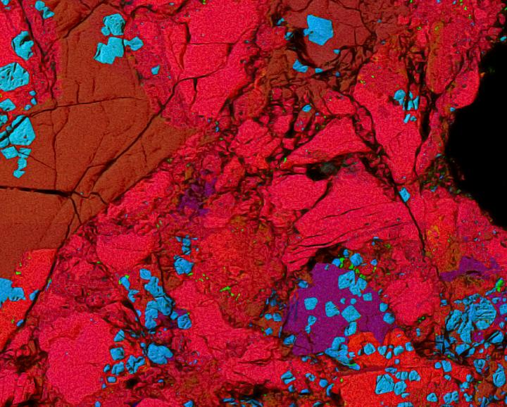 This false-color image shows a cross-section of the Allende meteorite, approximately one-hundredth of an inch (0.5 millimeters) across. It is peppered with inclusions that have a ceramic-like chemistry. Calcium is shown in red, aluminum in blue and magnesium in green. These inclusions contained an isotope of curium-247 that had a half-life of 15 million years. Evidence of curium was found due to a significant increase of uranium-235 that is produced from the decay of curium-247. Curium was created along with other heavy elements in supernovae. Image credit: François L.H. Tissot.