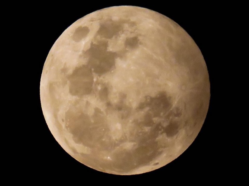 Yellowish full moon with slight shadow on right side.