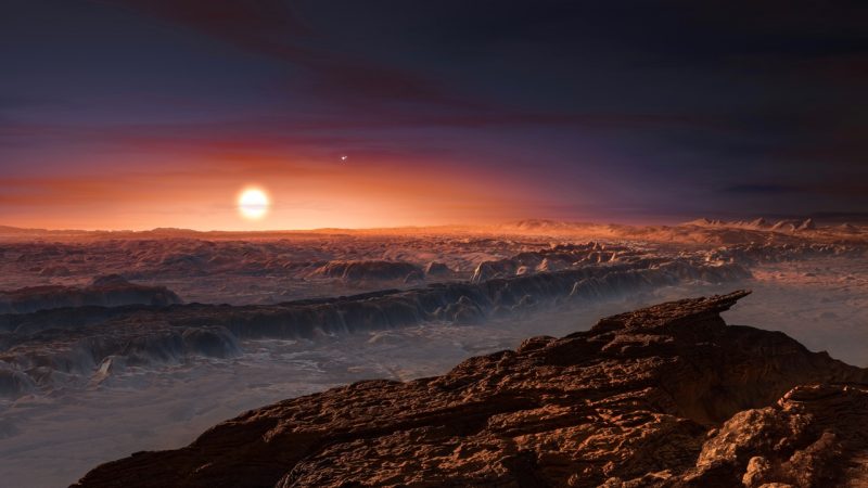 View larger. | This artist’s impression shows a view of the surface of the planet Proxima b orbiting the red dwarf star Proxima Centauri, the closest star to the Solar System. The double star Alpha Centauri AB also appears in the image to the upper-right of Proxima itself. Proxima b is a little more massive than the Earth and orbits in the habitable zone around Proxima Centauri, where the temperature is suitable for liquid water to exist on its surface.
