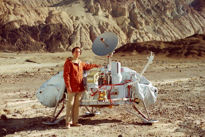 Man standing close to a lander of his same height. Desert in the background.