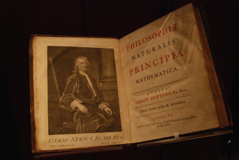 Small book, open, with portrait of Newton on left page and Latin title in red and black on right page.