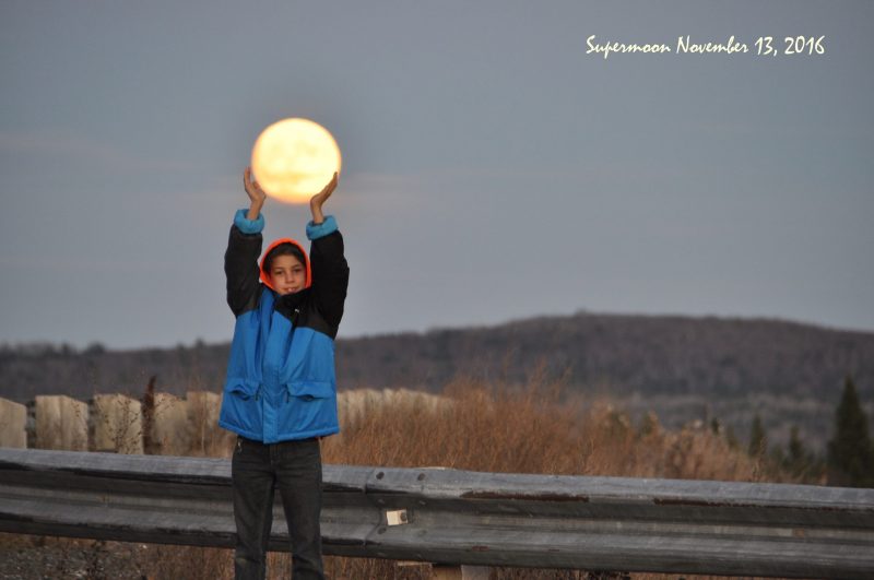 Stargazing tips: A person holding their arms up so it looks like they're holding the full moon in their hands.