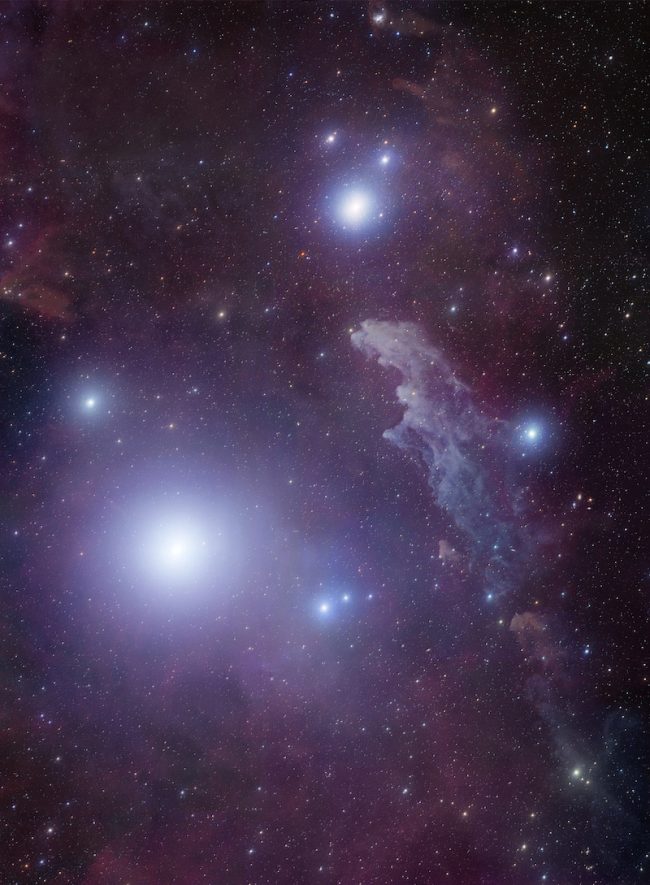 Several bright stars with blue halos near elongated blue cloud against star field.