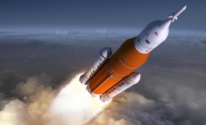 Large rocket with an orange stage and boosters on each side launching through the atmosphere on a tail of flame.