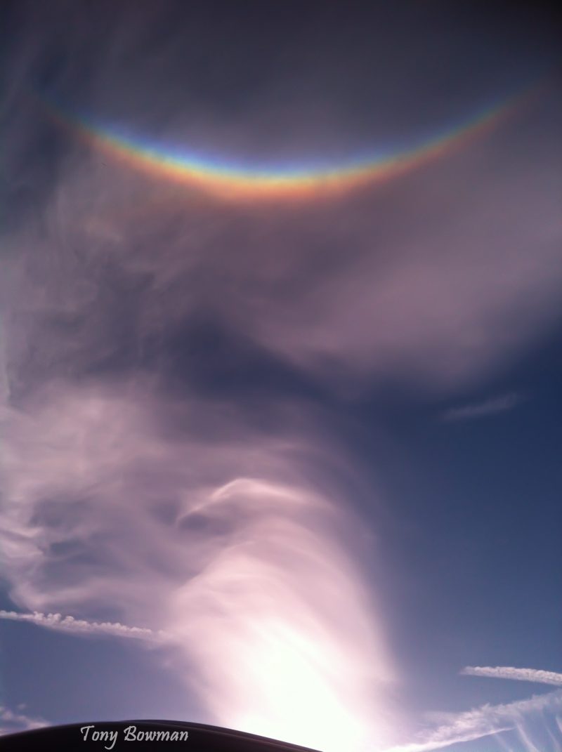 Partly cloudy sky with an upside down rainbow at the top of the photo.
