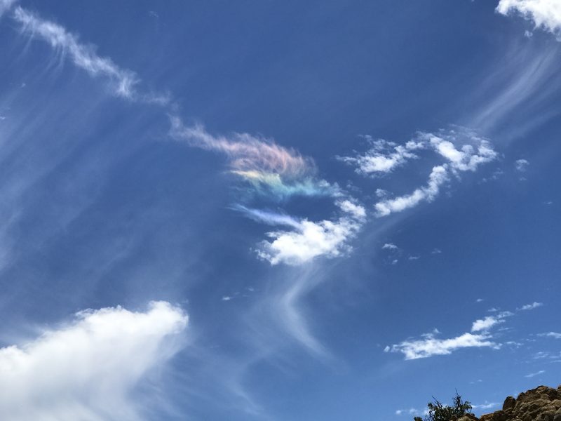 Streaks of wispy clouds, with short rainbow patch on one part.