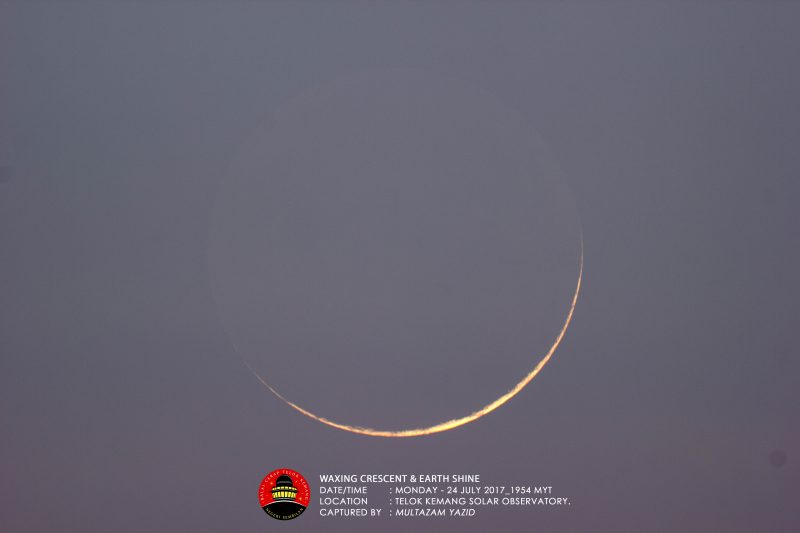 Large, very thin, yellowish crescent against a blue-gray sky.