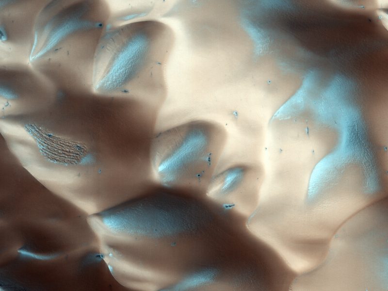 Undulating sand dunes on Mars with deposits of bluish white snow and ice.