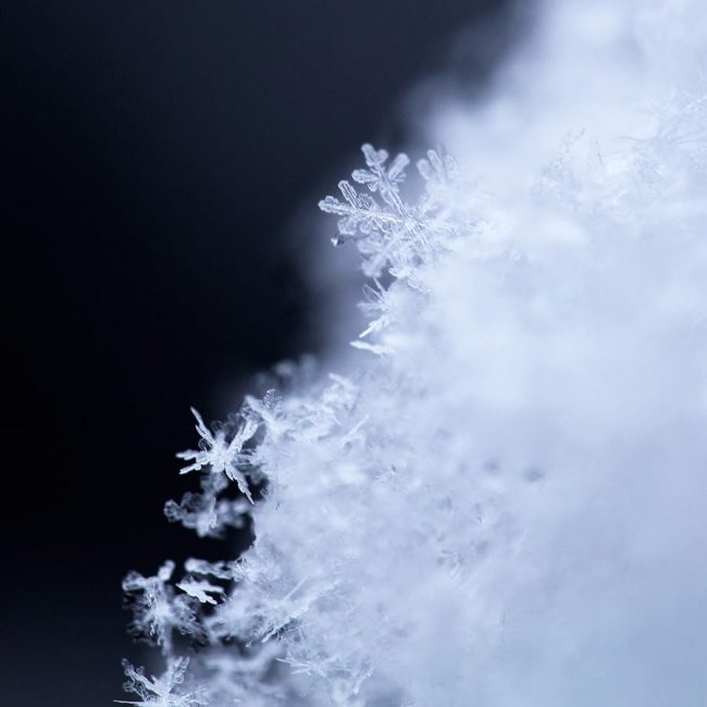 Tiny tumbled snowflakes on the edge of pile of snow.