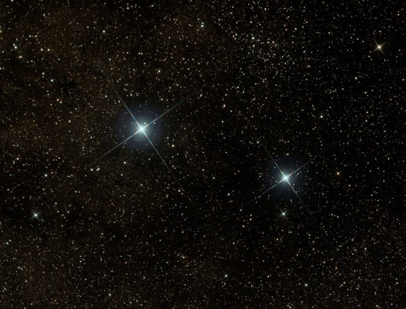 Photo showing two bright blue stars against a backdrop of very many fainter white stars.