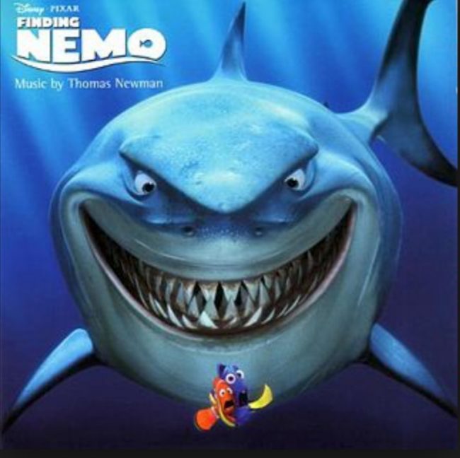 Grinning cartoon shark from movie Finding Nemo with 2 small fish in front.