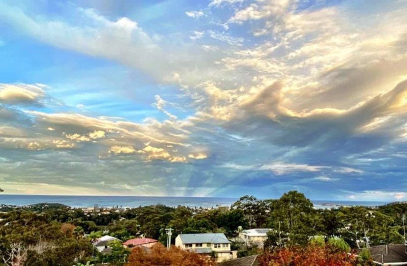 Blue sky over a town with rays emanating from the horizon.