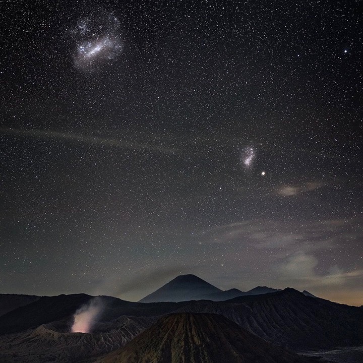 Photo of the Large and Small Magellanic Clouds over a smoking volcano at Bromo Semeru Tengger National Park, Java, Indonesia