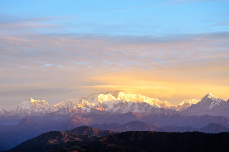 Dawn sky over wide panorama of jagged mountaintops.