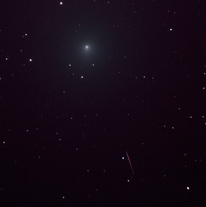 Dark sky with blurry point at the top and a thin red streak at the bottom.